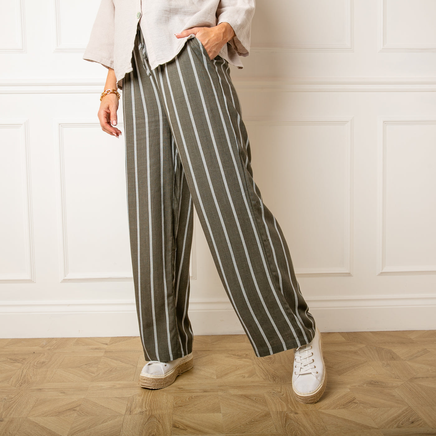 The khaki green Pinstripe Linen Trousers with side pockets and a wide leg silhouette 